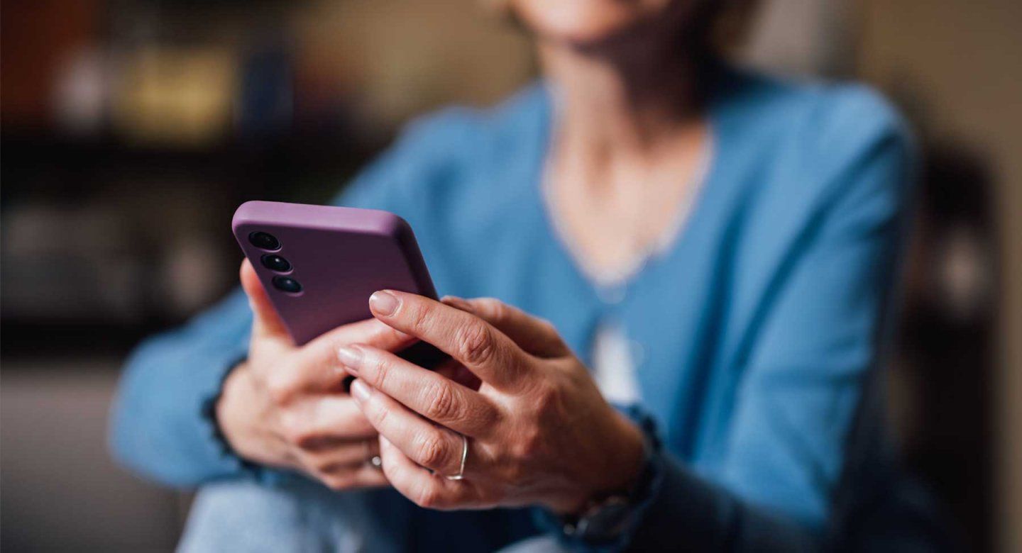 A middle-aged woman uses a smartphone.
