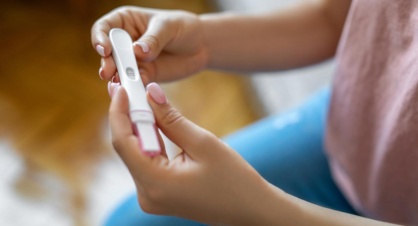 A woman's hands hold a positive pregnancy test.