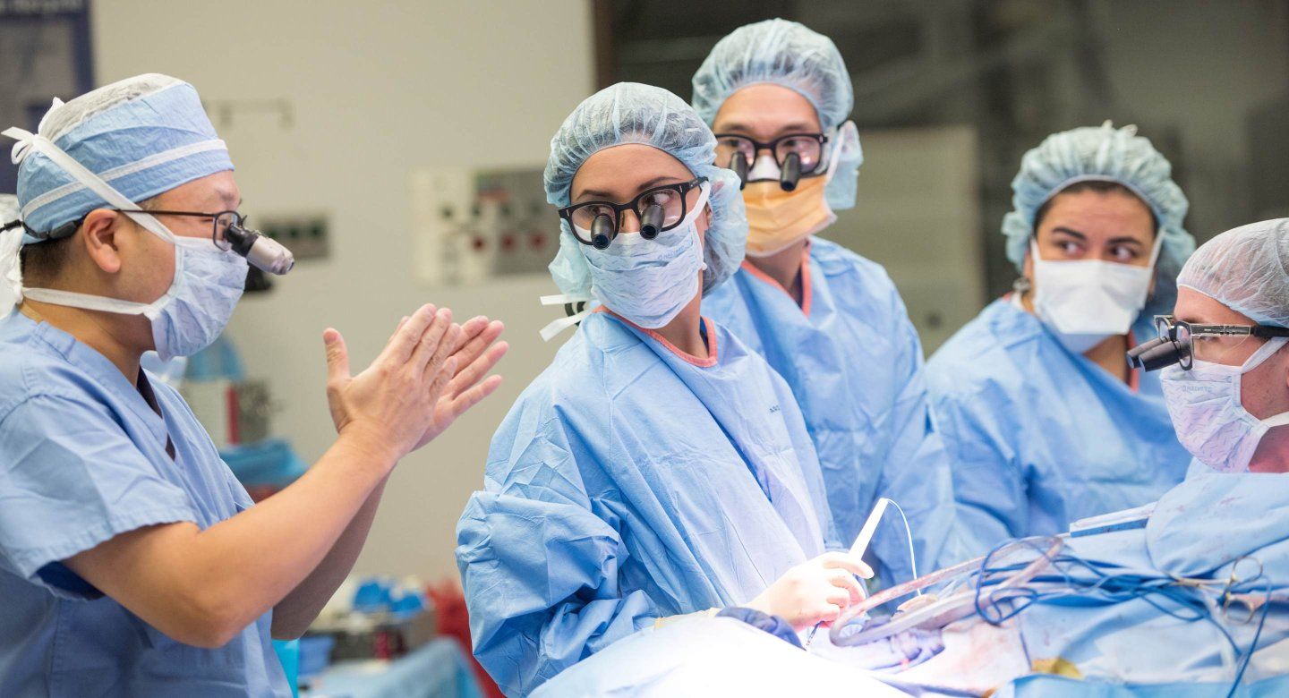 Group of surgeons look at lead medic during intensive surgery.
