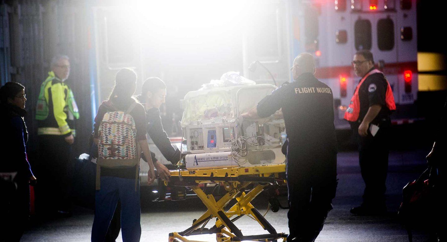 Emergency medicine professionals, including a flight nurse, transport an incubator for emergency medical attention.