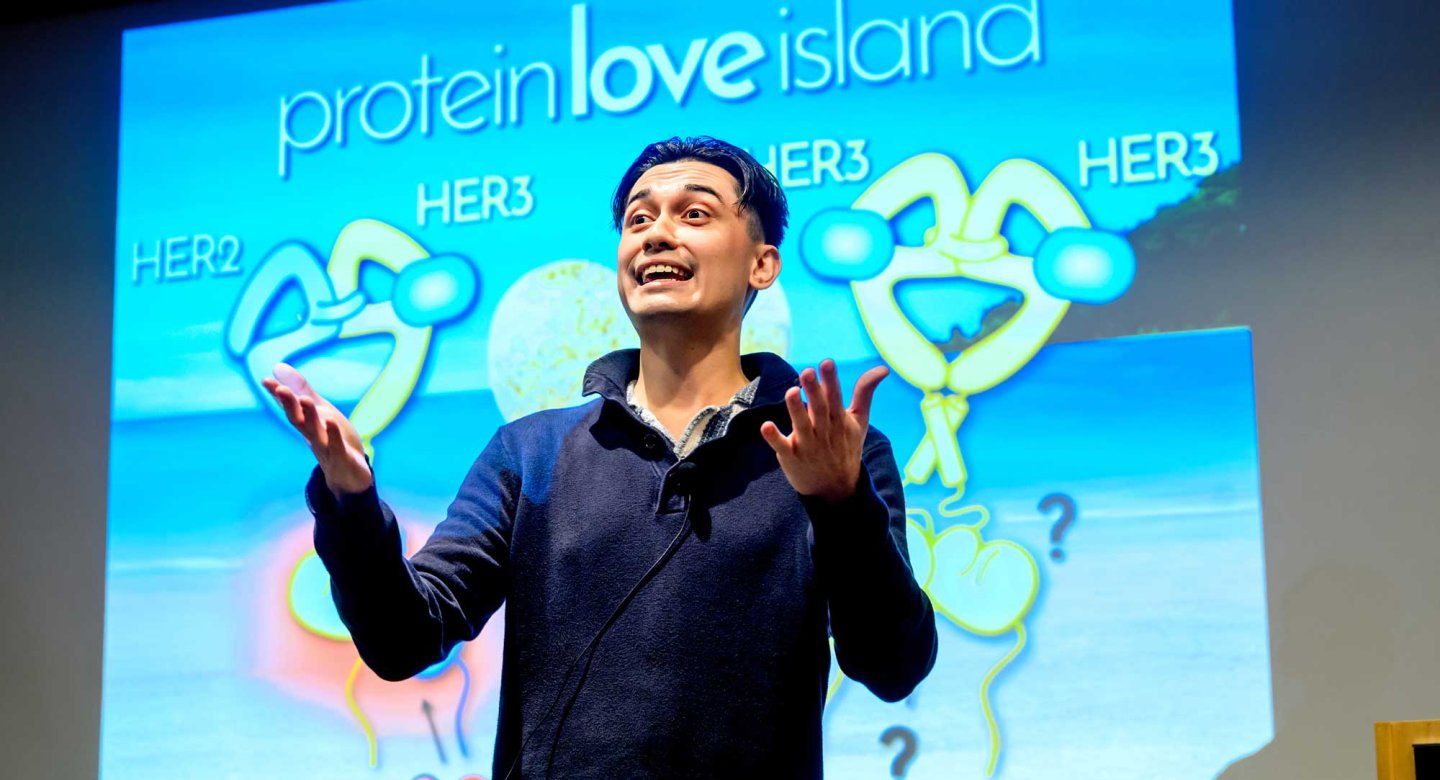 Grad Salm presentor Brandon Corteau delivers his talk in front of a projection screen.