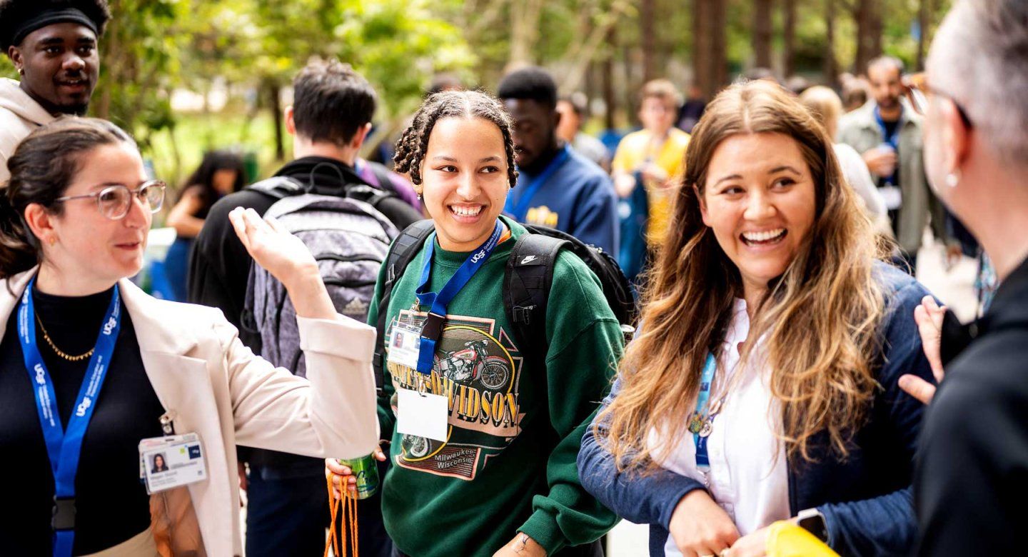A group of U C S F staff and graduate students smile as they stand outdoors during a fall celebration.