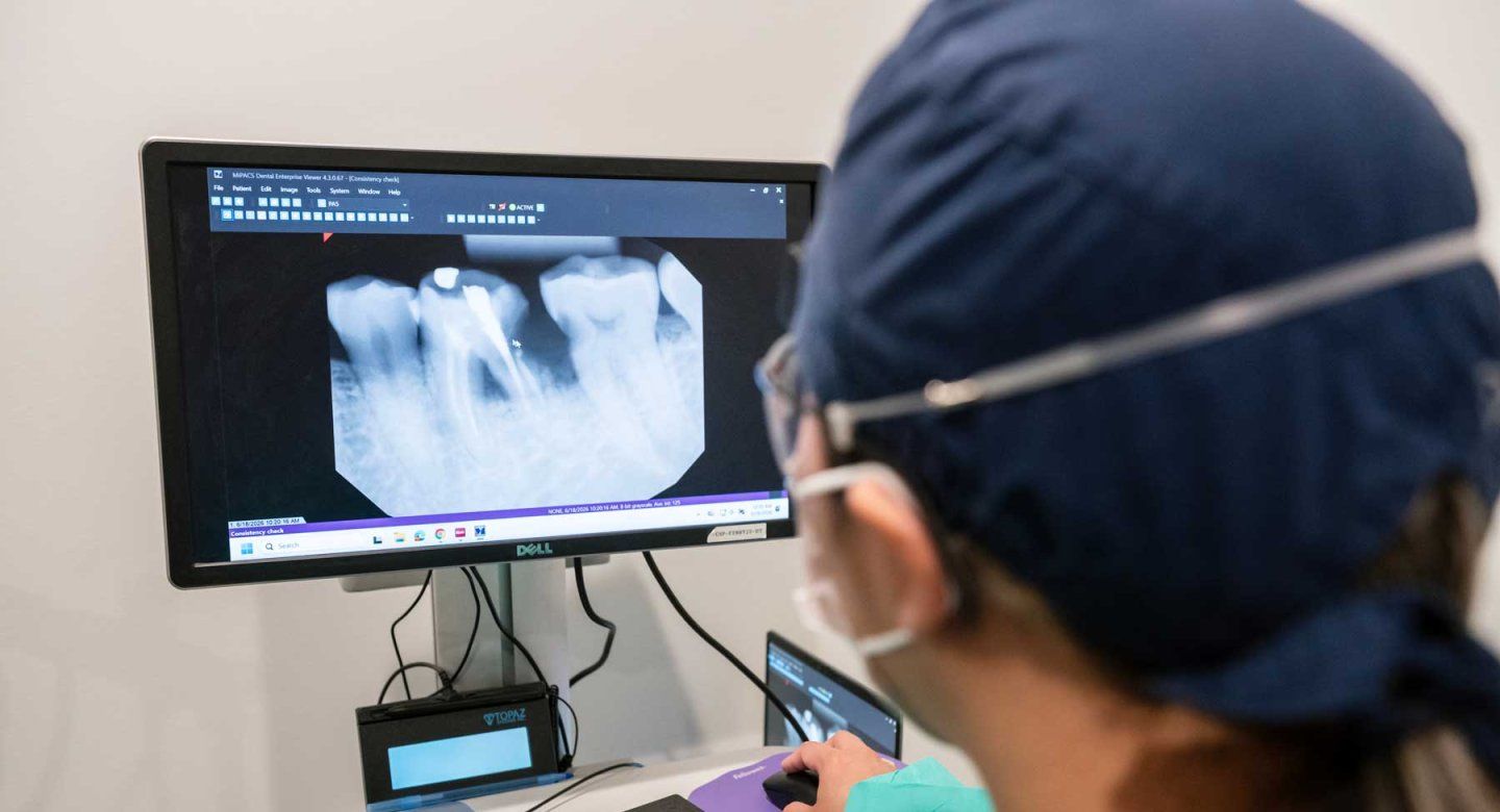 A dentists looks at dentals scans on a computer screen.