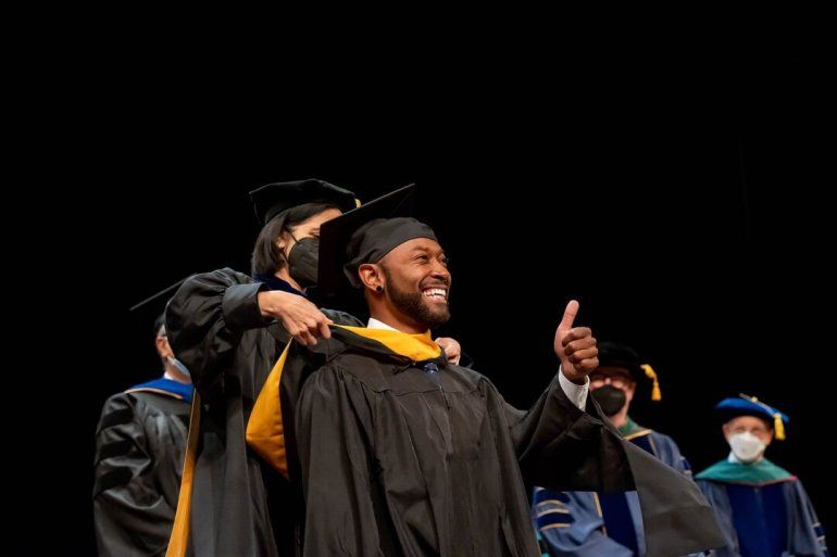 A graduate student receives his master's hood at the 2022 UCSF Graduate Division Commencement Ceremony