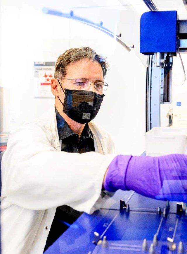 Sergio Baranzini wears a black mask while conducting research in his lab.