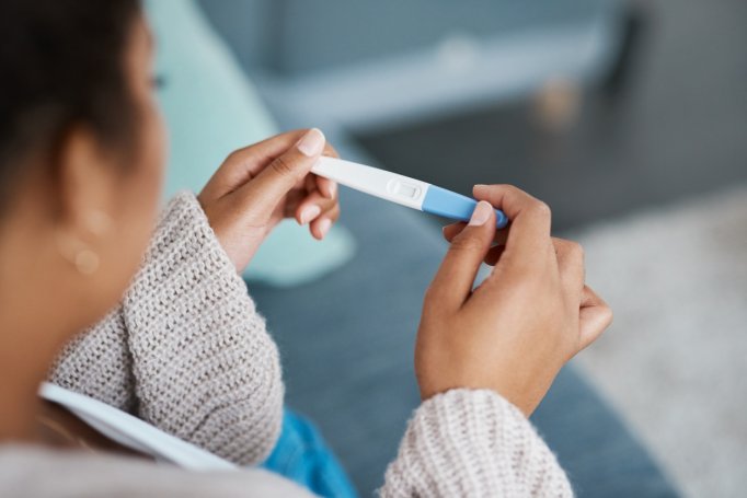 An unrecognizable woman looks down at a pregnancy test