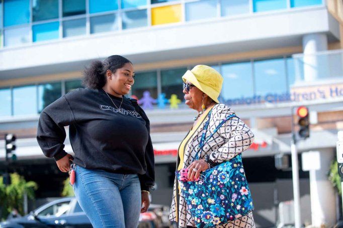 A young African American woman named Brooklyn Haynes and her grandmother cross a street together outside UCSF Benioff Children's Hospital Oakland.