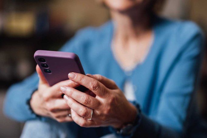 A middle-aged woman uses a smartphone.