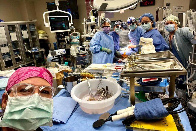 A group of all women surgeons and medical professionals take a selfie during a surgery.