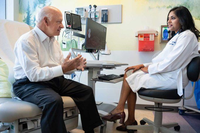 Dr. Aparajita Singh sits with her patient Bill in a well-lit examination room.