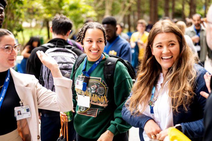 A group of U C S F staff and graduate students smile as they stand outdoors during a fall celebration.