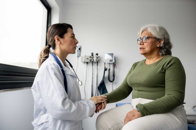 A doctor comforts an elderly female patient.