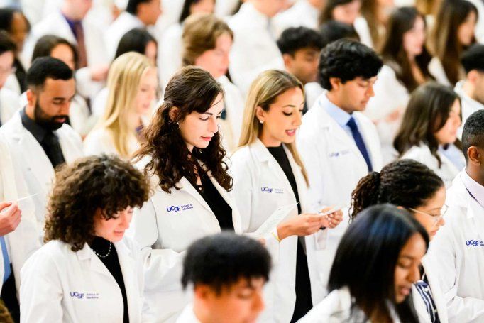Medical students wearing white coats recite an oath.