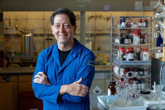 Kevan Shokat wears a blue lab coat as he stands in his lab at U C S F.