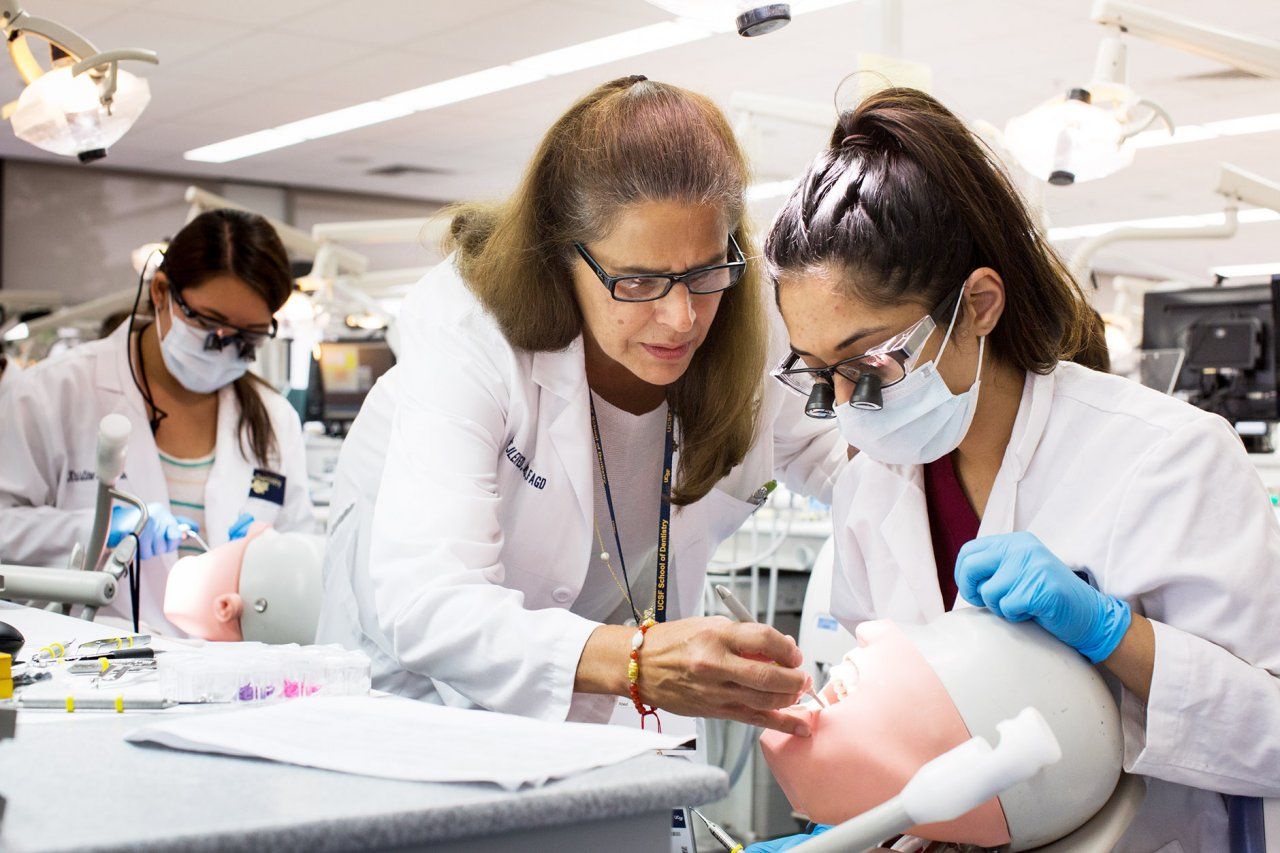 Dentistry professor instructs student in a simulation lab