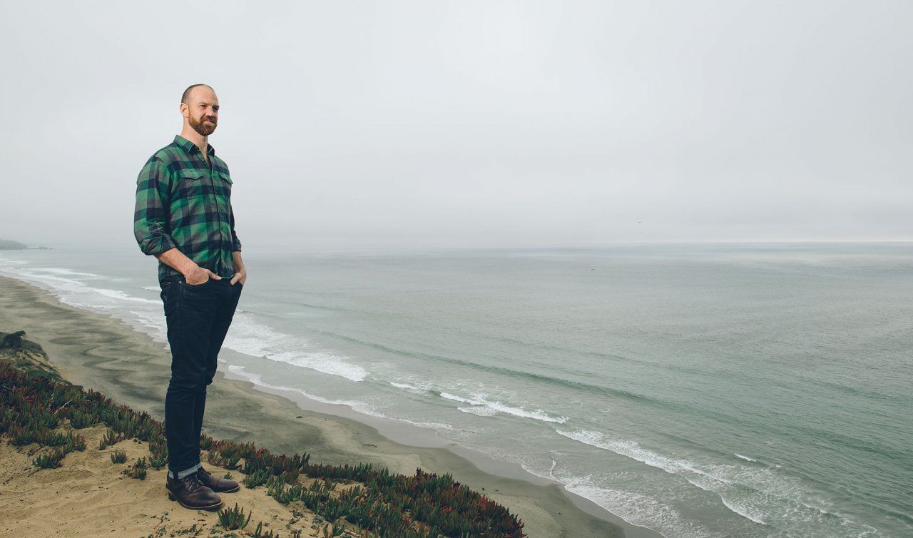 Matthew Wetschler, MD, stands on a sandy cliff overlooking the ocean.