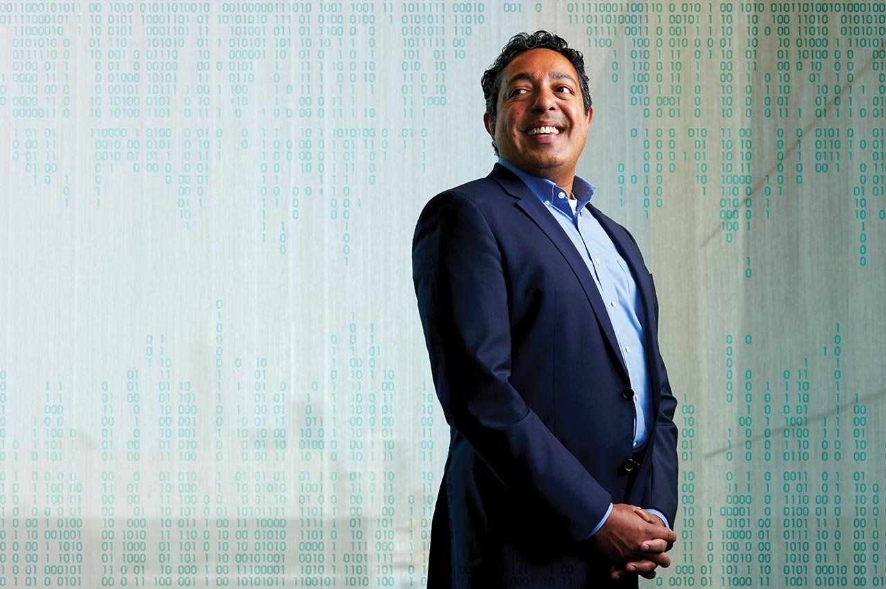 Portrait of Atul Butte with binary code illustration in background.