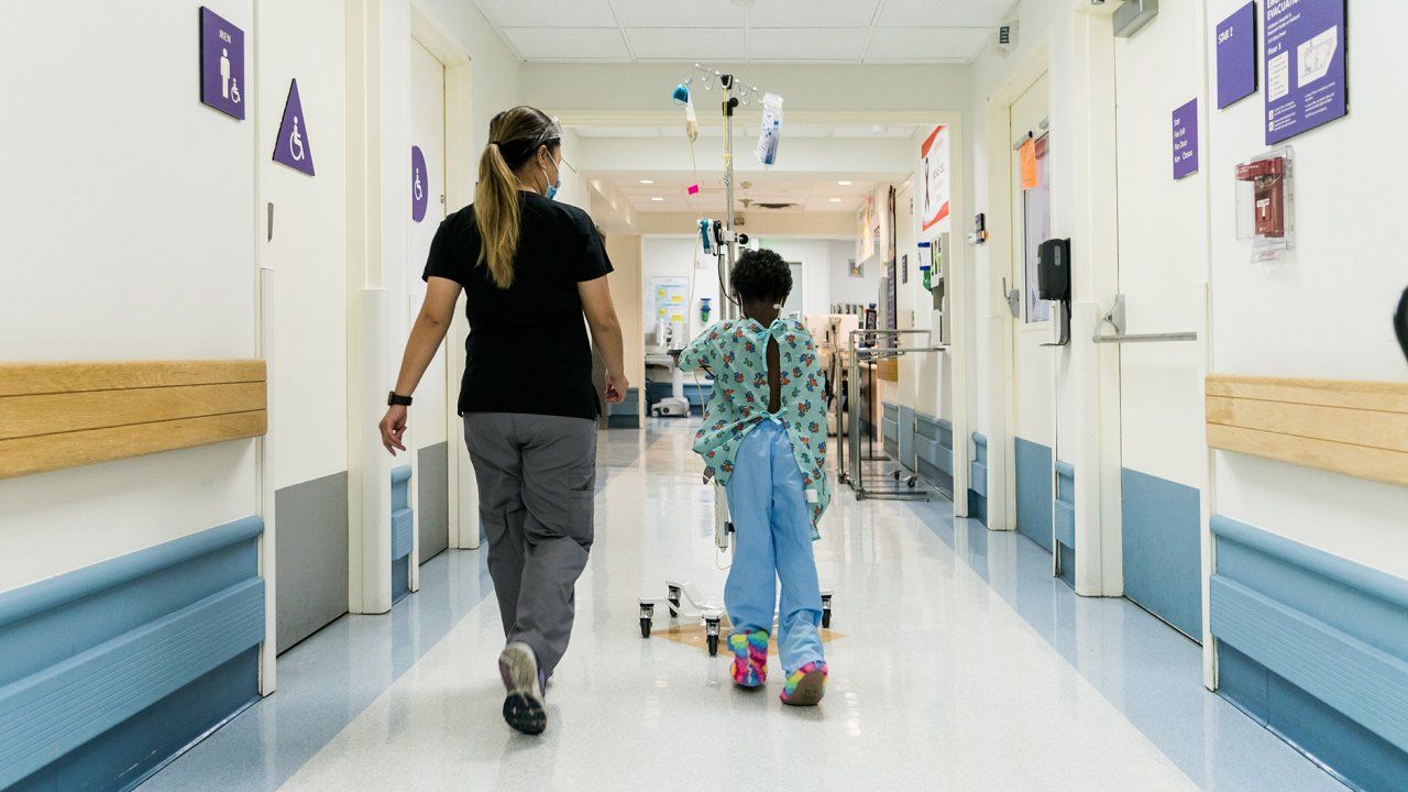 woman walks down a hallway with a young patient