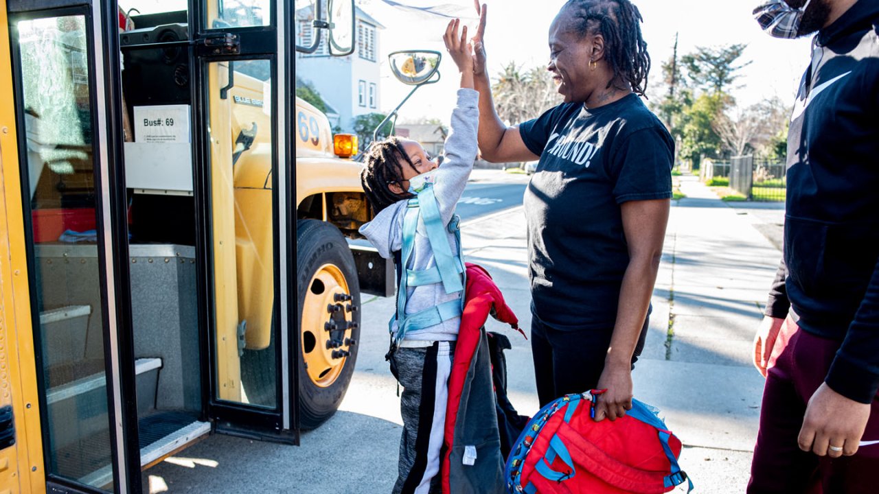 Rashetta Higgins high fives her youngest son outside of the school bus