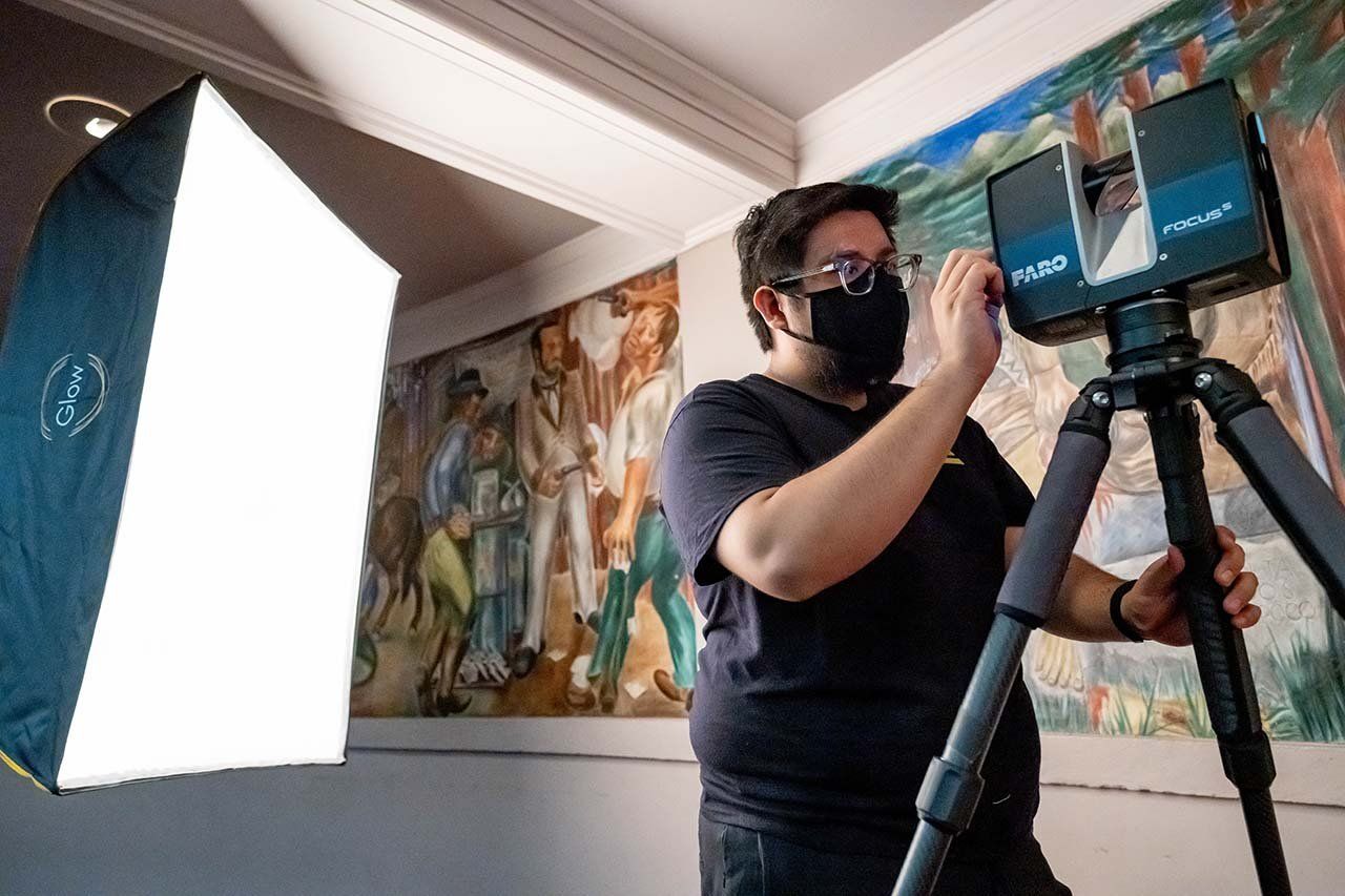 An archivist using a camera and a light to capture the murals