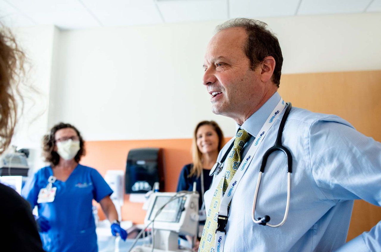 Stephen Gitelman talks with a nurse coordinator and nurse during a patient appointment.