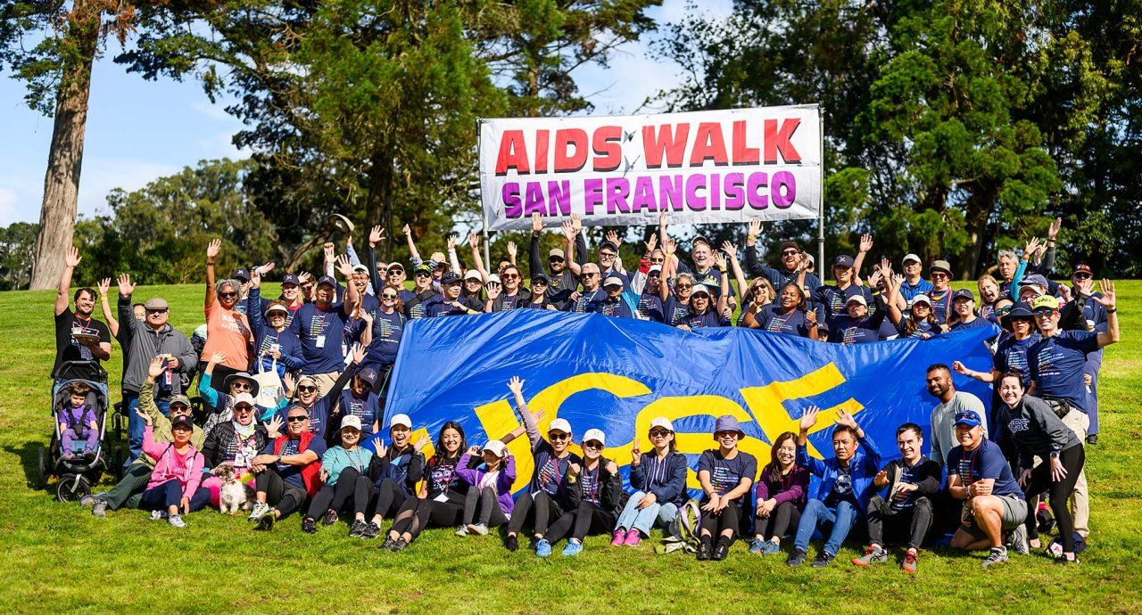 A large crowd of UCSFers poses for a group photo with a sign that reads AIDS Walk San Francisco and a huge UCSF banner