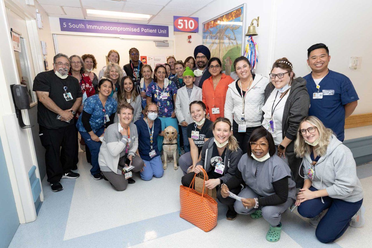 A young male patient named Manwar and his family pose with numerous medical staff who are part of a behavioral and mental health team at UCSF Benioff Children's Hospital Oakland.