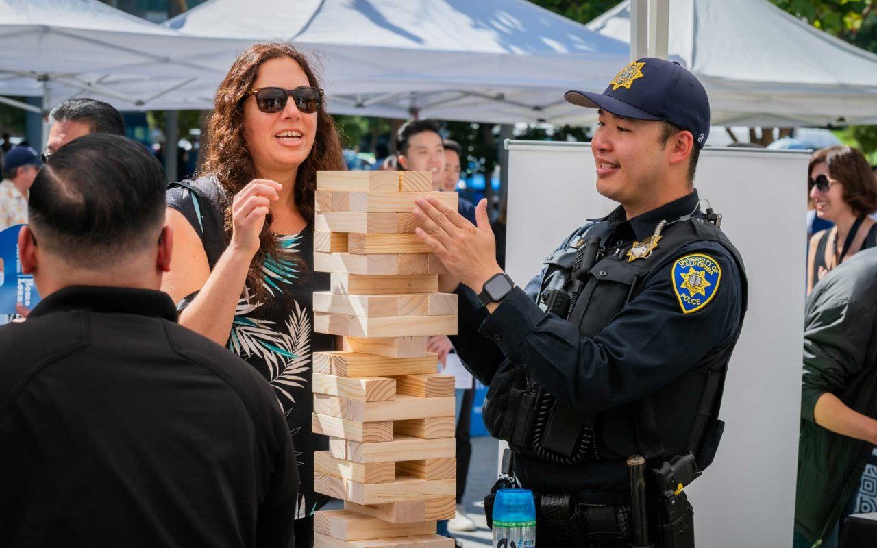 UCSF staff, including a police officer, laugh as they play a game of jenga together.