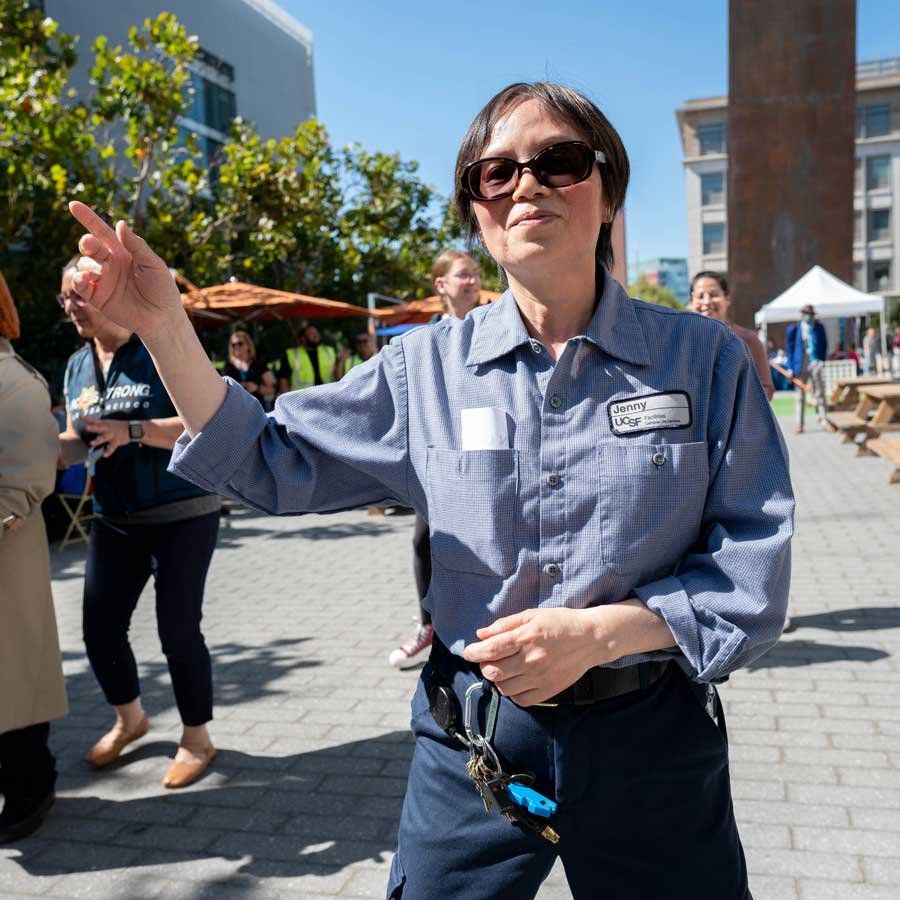 Jenny Low, a senior custodian, participates in a line dance outdoors. 