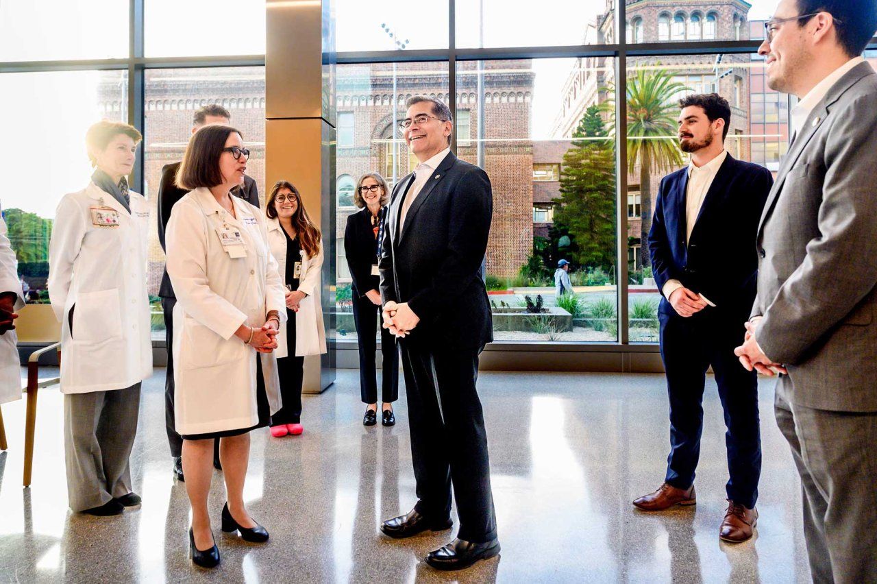 U.S. Health and Human Services Secretary Xavier Becerra speaks with doctors at a light-filled atrium in Zuckerberg San Francisco General Hospital.