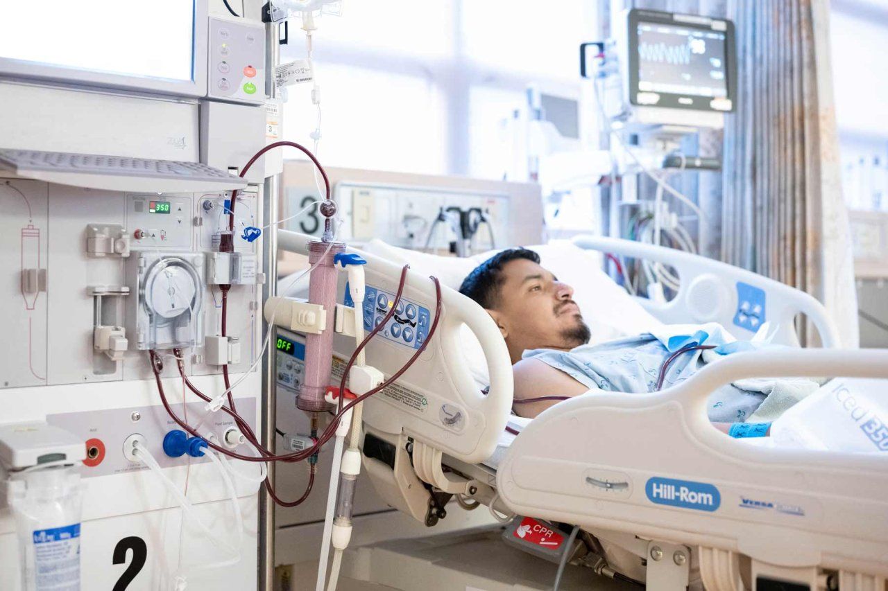 A young male patient lies on a hospital bed as a hemodialysis machine helps work as an artificial kindey after his kidney transplant surgery.