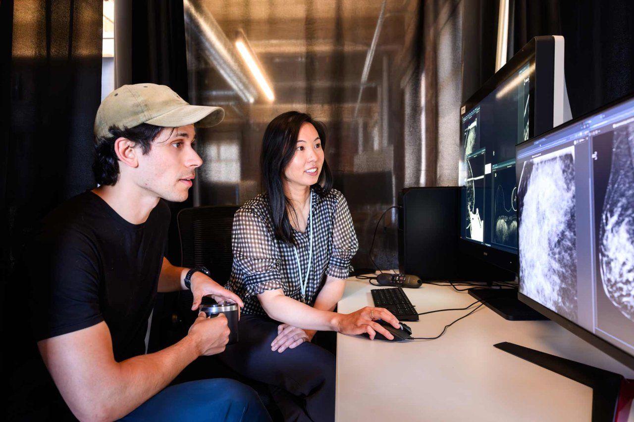Researchers Maggie Chung and Adam Yala look at a mammogram scan on a computer screen.