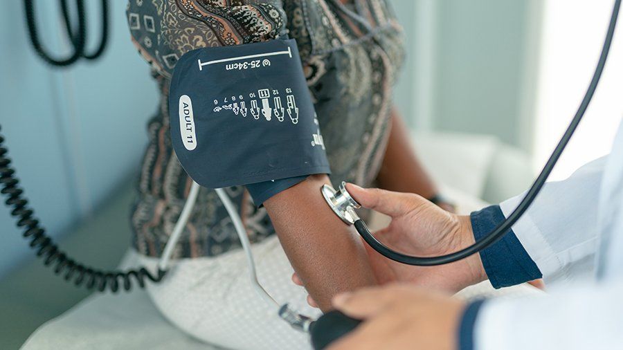 White doctor takes a Black patients blood pressure