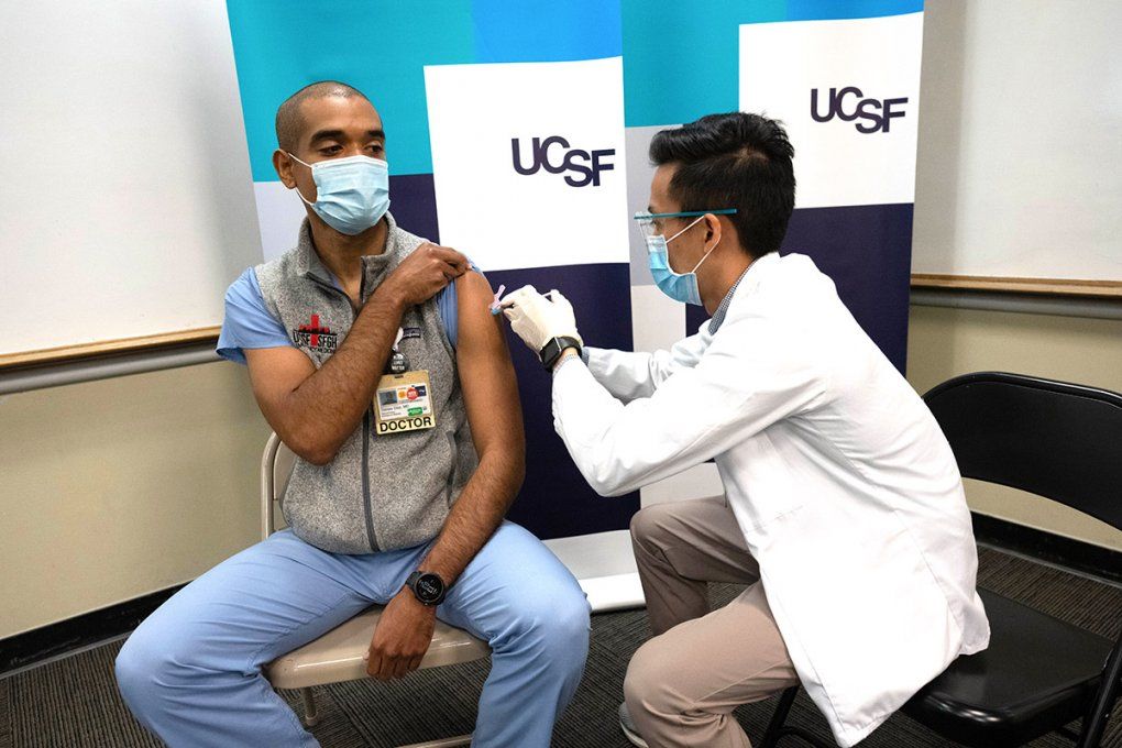 A UCSF doctor rolls up his sleeve to receive his shot