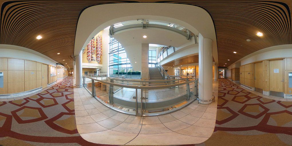 A view of the Genentech Hall atrium from the second floor showing a bright stairwell and a hanging chandelier resembling a genome