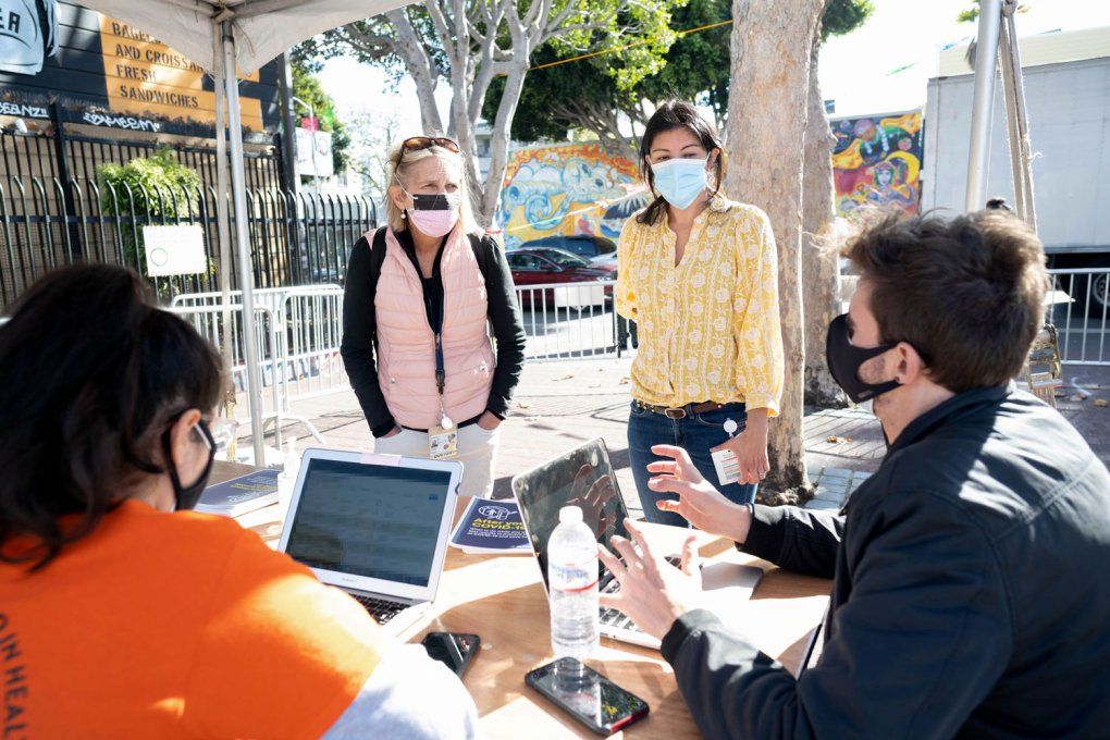 Two doctors speak with volunteers at a COVID testing tent in the Mission District of San Francisco