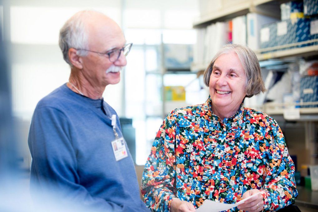 Morton Cowan (left) and Jennifer Puck (right) stand in a lab.