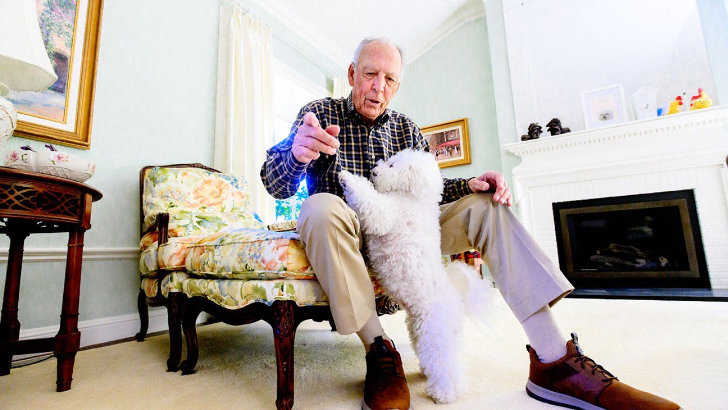 Don Onken plays with his dog in his living room