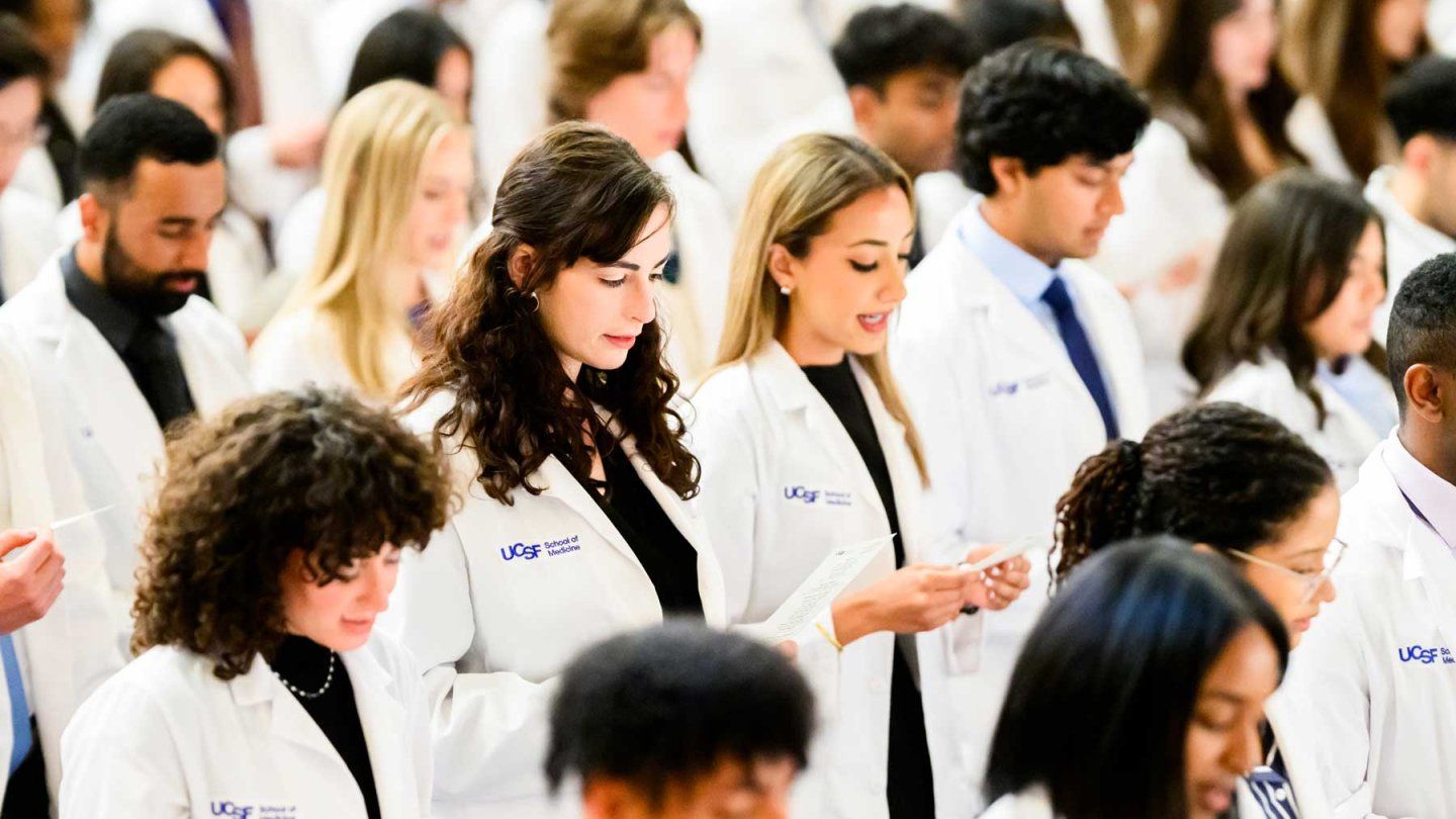 Medical students wearing white coats recite an oath.