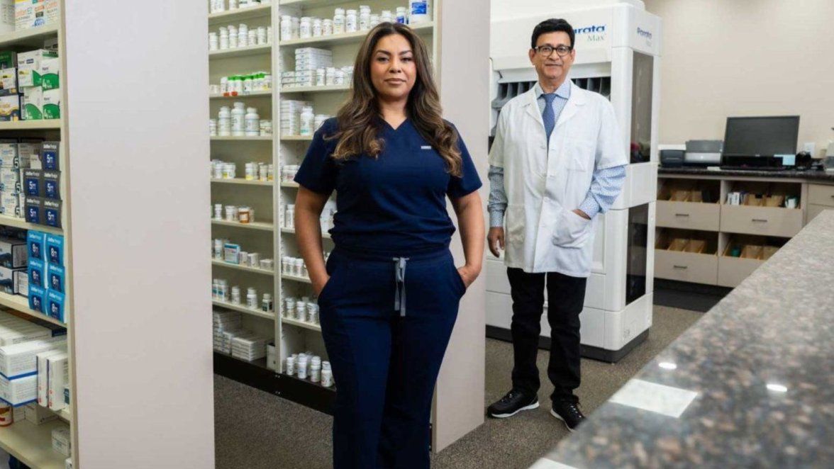 Two pharmacists surrounded by shelves of drugs posed for camera.