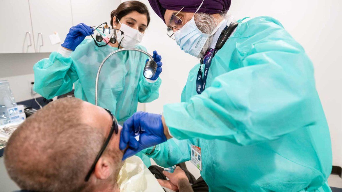 Two dental workers treat a patient.