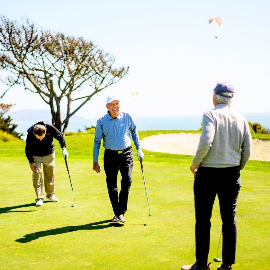 Don Onken walks between two friends on the golf course while laughing