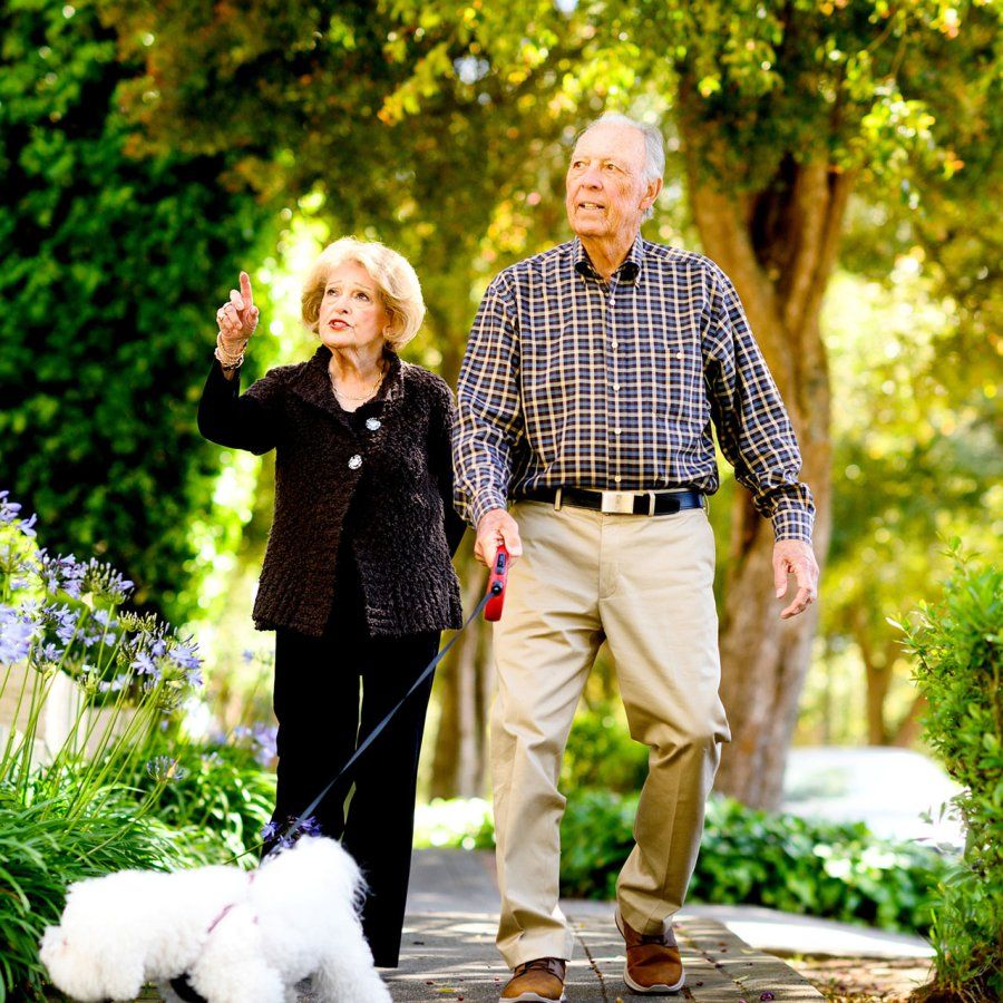 Don Onken walks down a treelined street with his wife and dog