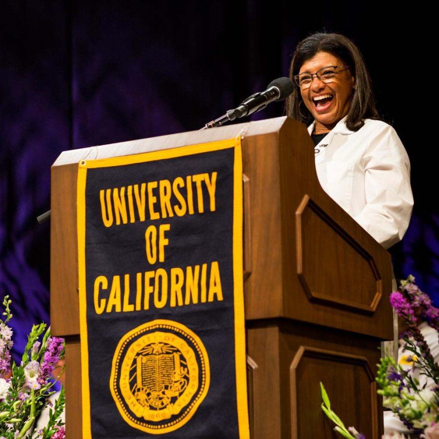 A woman smiles enthusiastically behind a podium.