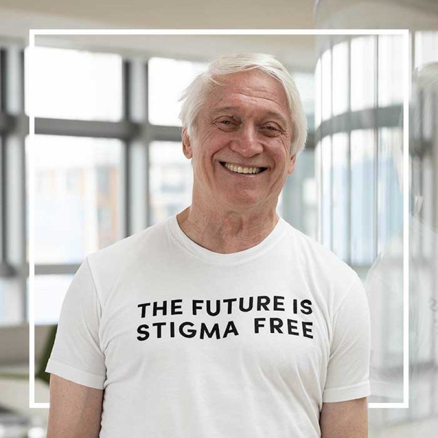 Steve Hinshaw stands in a sunlit room wearing a t-shirt that reads "The Future is Stigma Free."