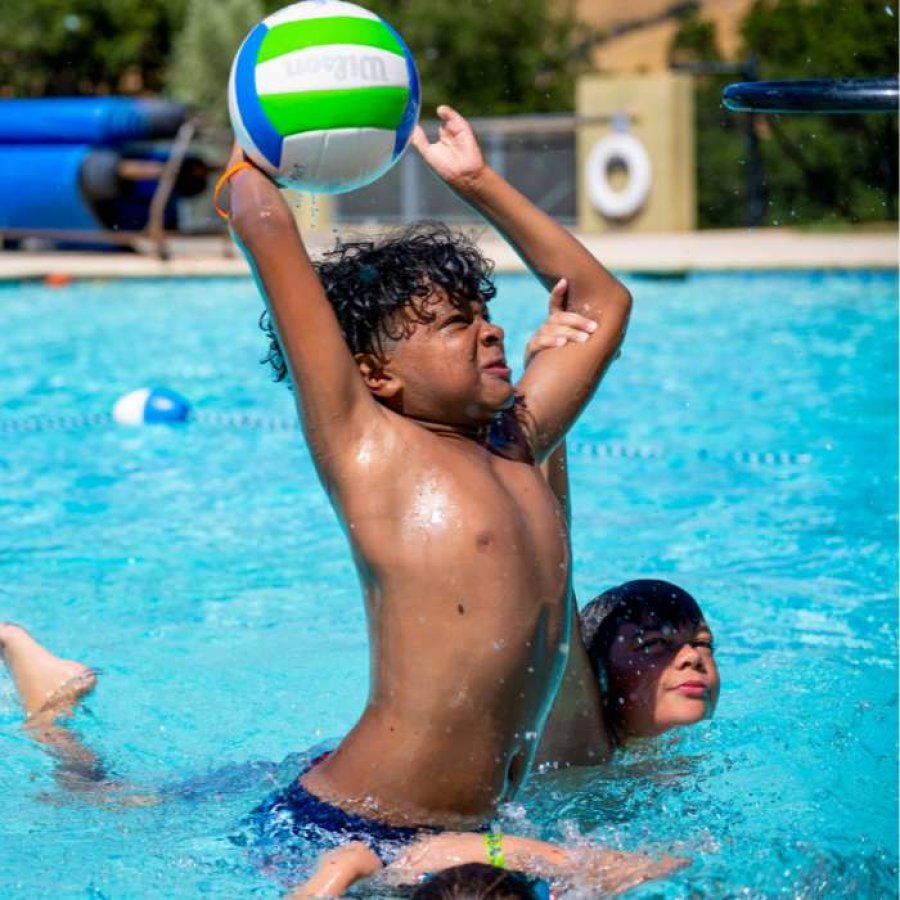 Boy throws ball in swimming pool