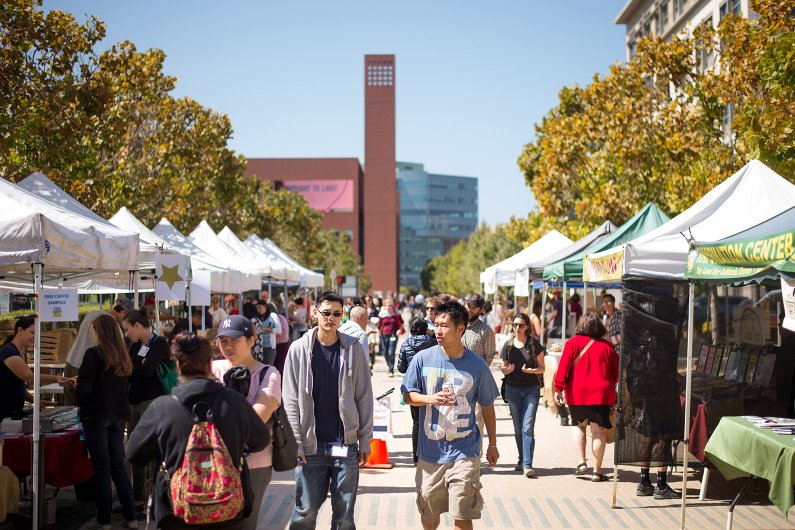 Two students walk through a farmer's market on the Mission Bay campus