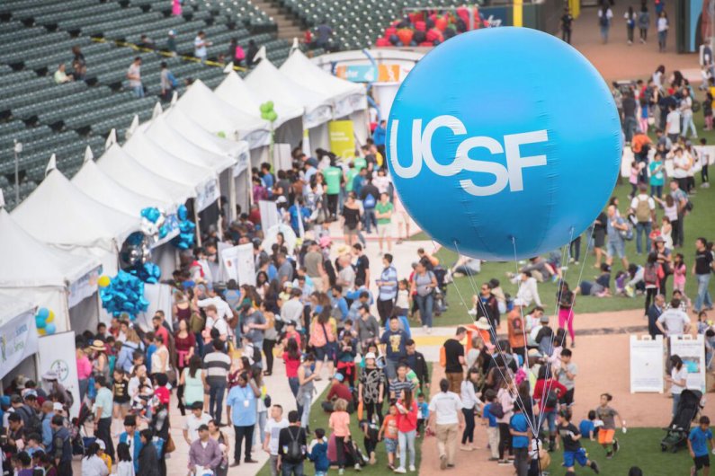 Attendees gather at AT&T Park to learn about science during the 8th annual Bay Area Science Festival Discovery Day 2018 in San Francisco. A large blue balloon that reads "UCSF" is in the center. 