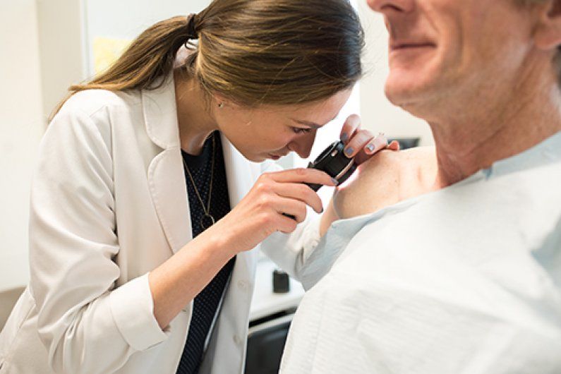 Doctor performing skin cancer exam. 