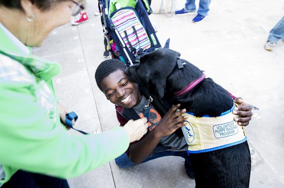 Keon Stewart, 14, and a support dog, on the dog's vest is a lable "voulunteer puppy raising program" 